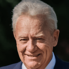 A man with white hair and wearing a suit.