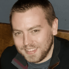 A man with a beard and mustache smiling for the camera.